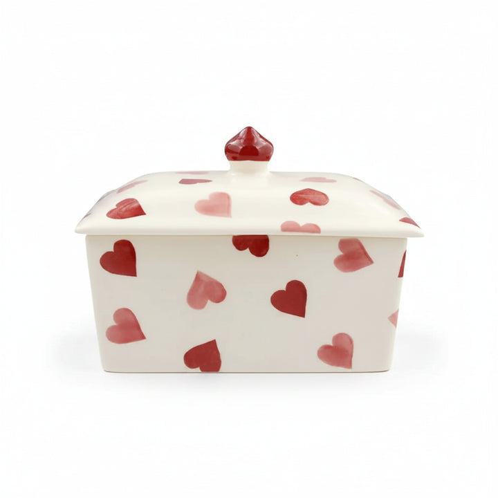 White ceramic butter dish with red heart patterns on a white background