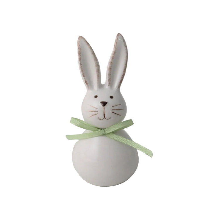 White ceramic bunny with a green ribbon on a gray background