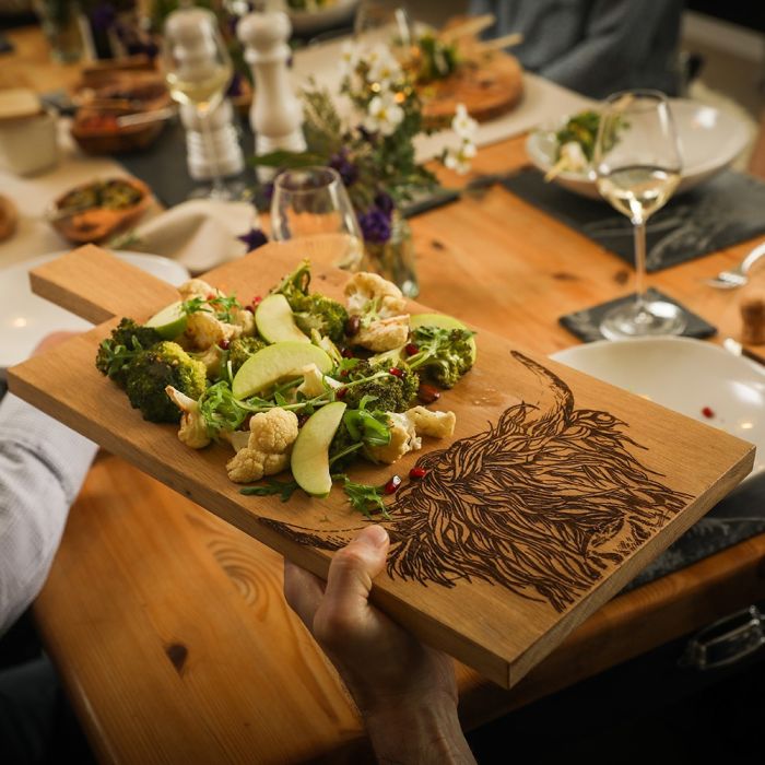 Large oak serving paddle with Highland cow design from Selbrae House, perfect for cheese and charcuterie displays.