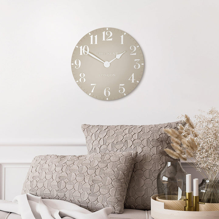 Arabic wall clock with sand-colored face by Cornucopia Home and Gift, featuring artistic design and bold Arabic numerals.