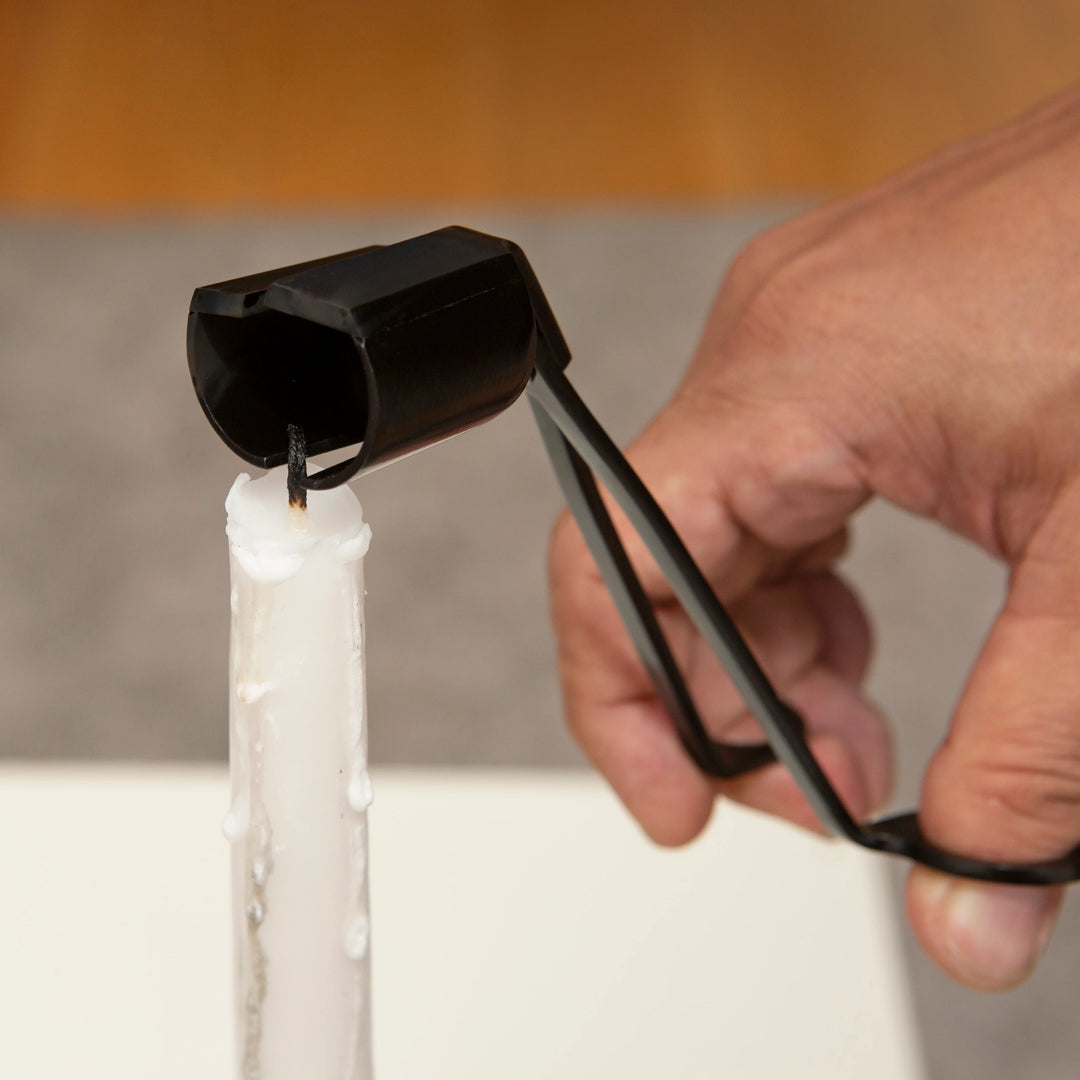 Kikkerland 3-in-1 candle tool with multiple functions, shown in action, used for lighting, trimming, and snuffing candles.