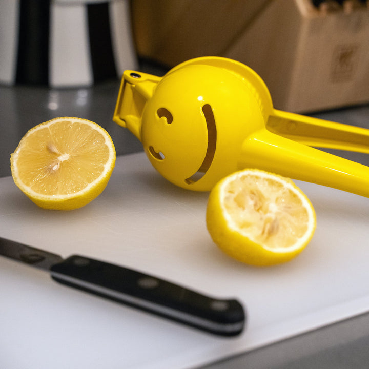 Kikkerland Smiley Face Citrus Squeezer in bright yellow with a cheerful smiley face design, ideal for juicing lemons and oranges.