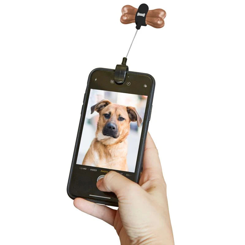 Kikkerland Dog Treat Selfie Clip attached to a phone, featuring a playful design for capturing fun pet moments.