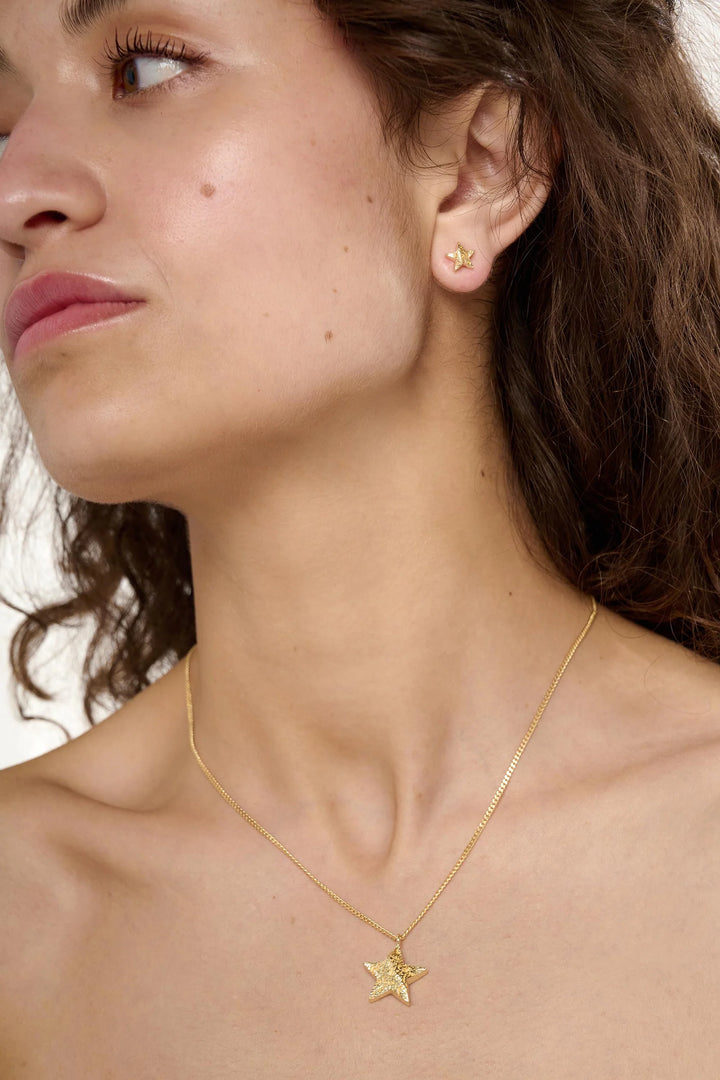 Gold Cosma Necklace by Tutti &amp; Co featuring a delicate chain and stylish pendant, displayed on a neutral background.