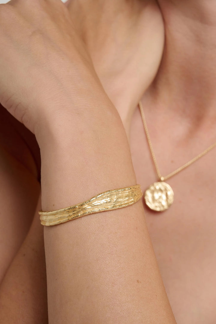 Gold Driftline Bangle by Tutti &amp; Co featuring a sleek, modern design on a clean background.