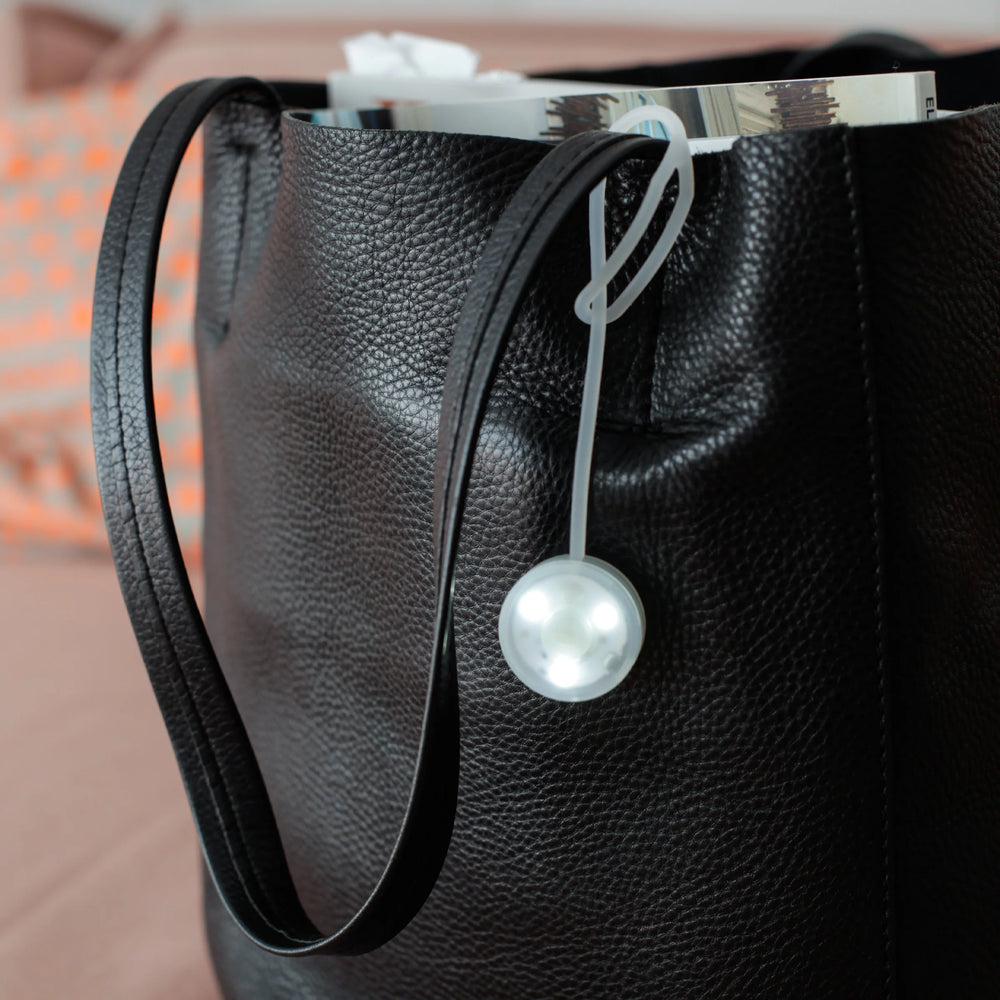 Kikkerland Bag Light from Cornucopia Home and Gift, compact purse-shaped LED light with a clip for portable illumination.