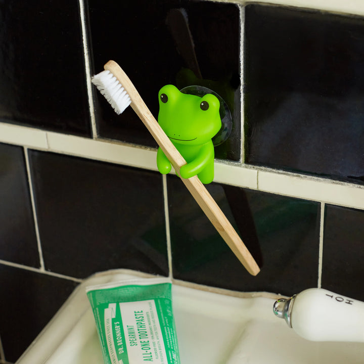 Kikkerland frog-shaped toothbrush holder with multiple slots, designed by Cornucopia Home and Gift, placed on a bathroom countertop.