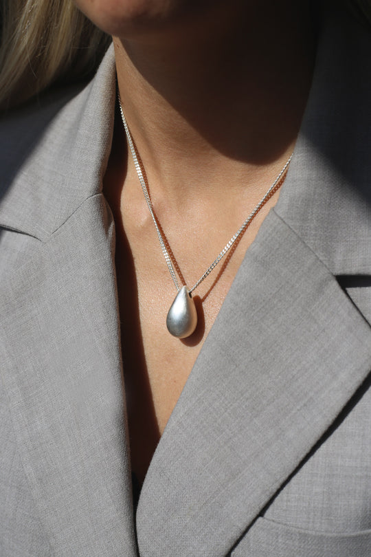 Silver Hush Necklace by Tutti & Co featuring a delicate chain and minimalist pendant, displayed against a neutral background.