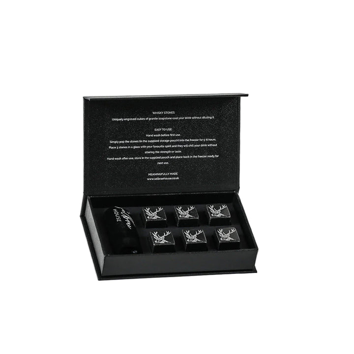 Six Selbrae House whisky stones in a clear glass, with a textured stone appearance, designed to chill drinks without dilution.