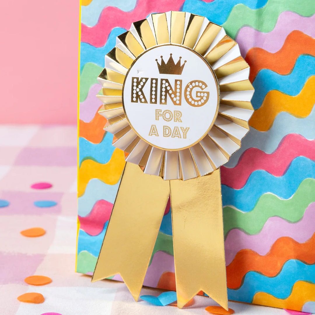 Gold "King For A Day" Birthday Rosette Badge from Talking Tables, featuring a shiny gold finish and decorative ribbon design.