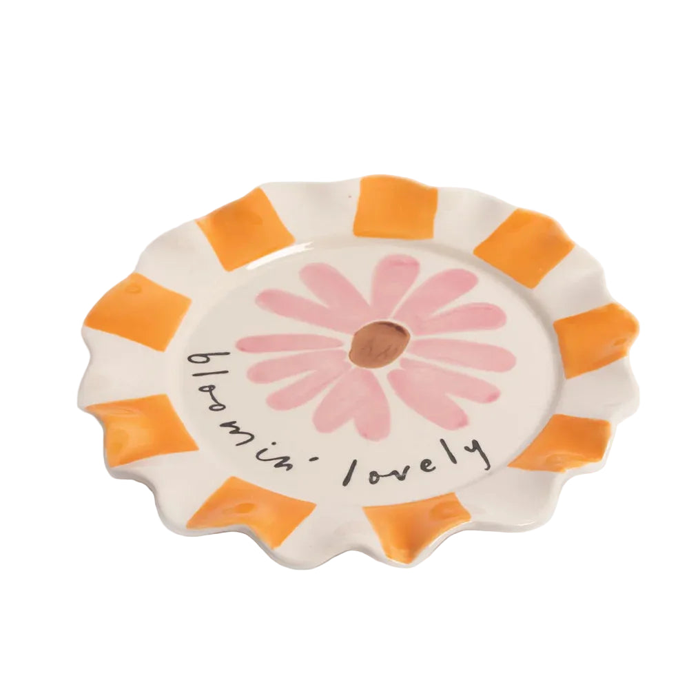 Ceramic plate with a pink flower design and orange stripes on a white background