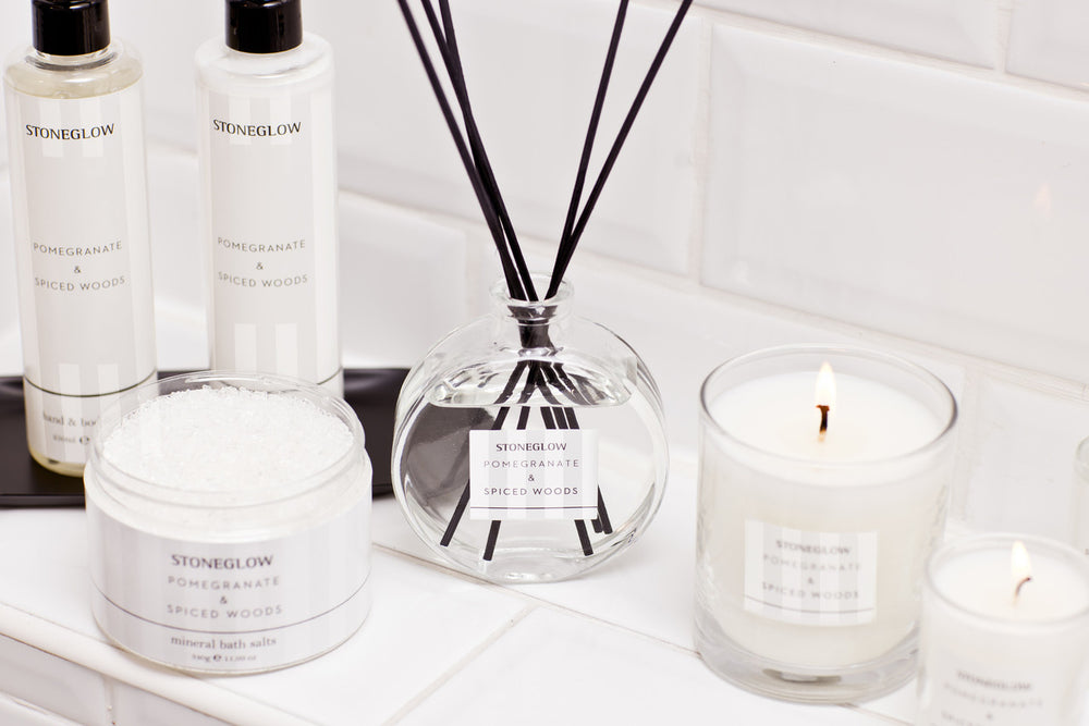 Stoneglow Modern Classics Pomegranate and Spiced Woods reed diffuser in 120ml glass bottle with reeds, styled in a cozy home setting.