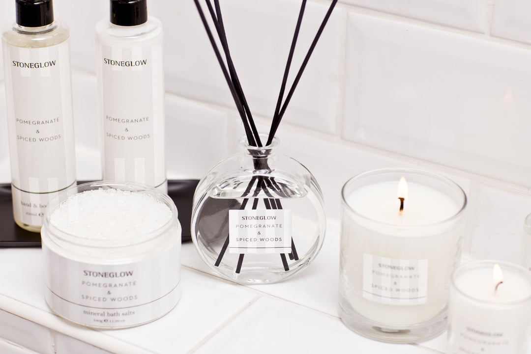 Stoneglow Modern Classics Pomegranate and Spiced Woods reed diffuser in 120ml glass bottle with reeds, styled in a cozy home setting.