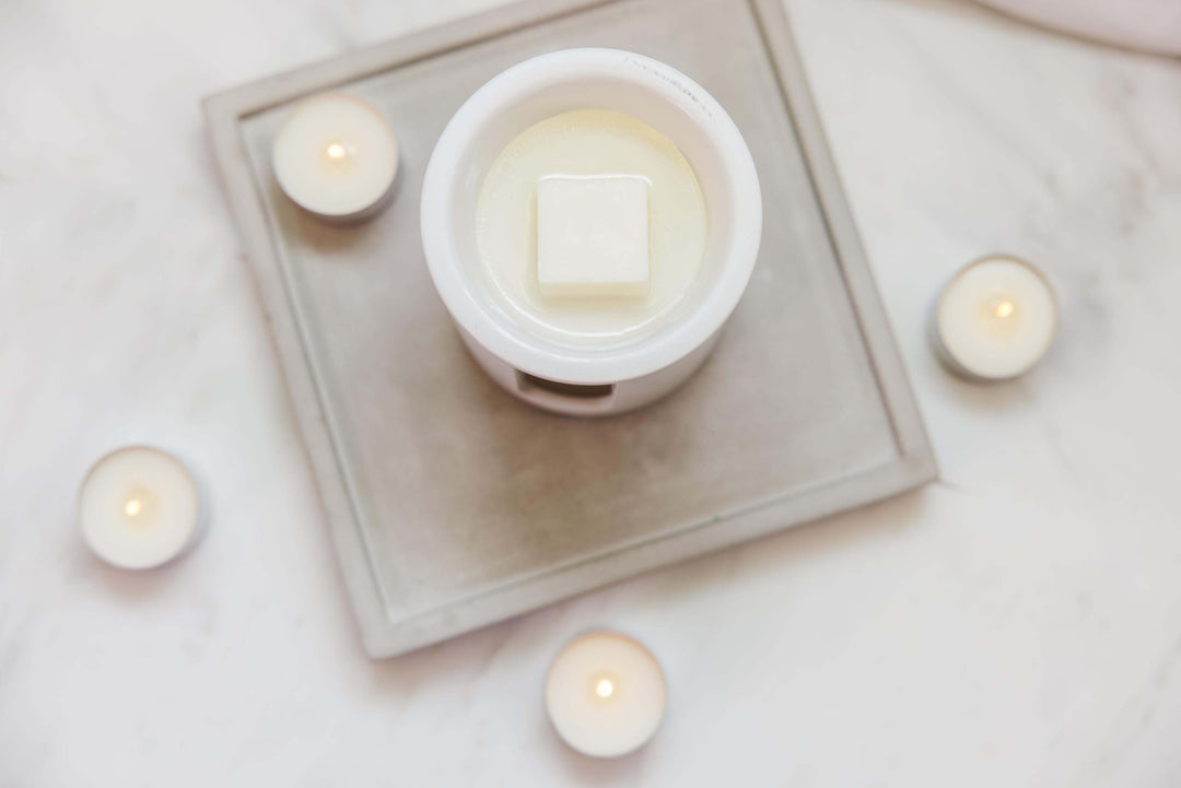 Stoneglow Pomegranate &amp; Spiced Woods scented tealights in decorative holders, creating a warm, inviting ambiance.