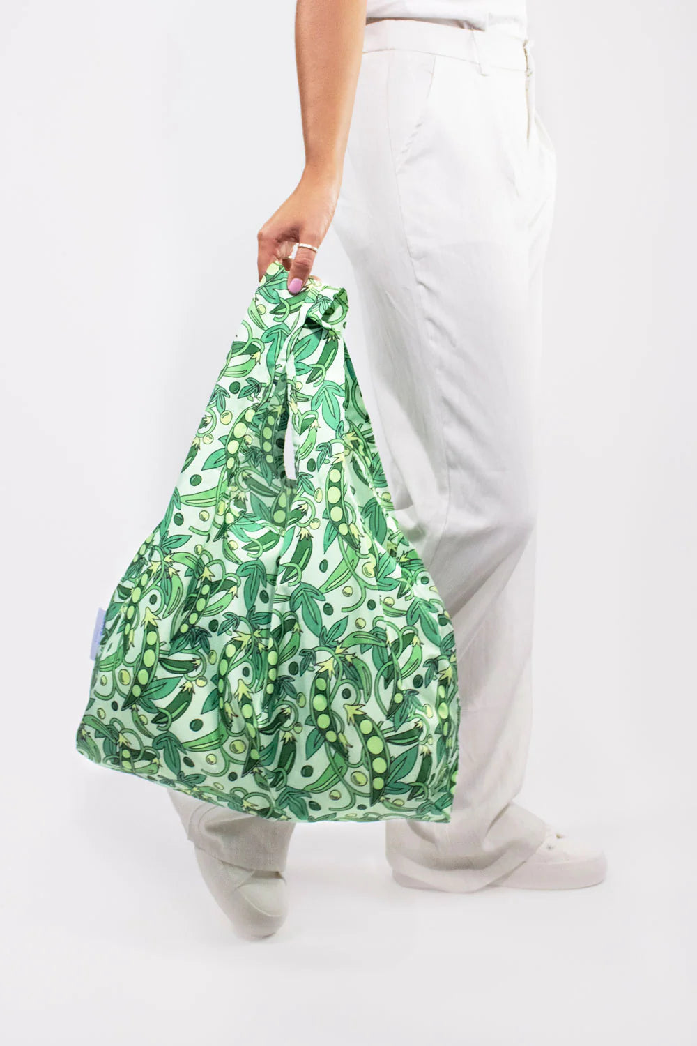 Close-up of medium-sized reusable bag filled with fresh green peas, showcasing the eco-friendly design of a Kind Bags product.
