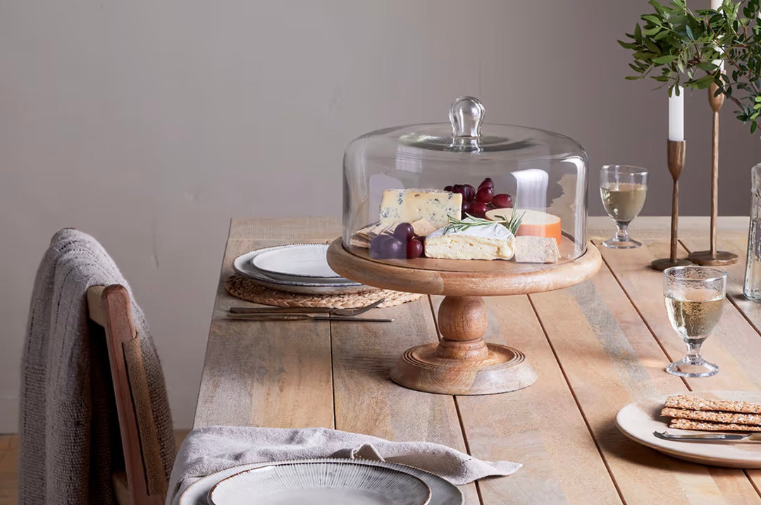 Nkuku recycled glass dome cake stand with mango wood base, perfect for showcasing desserts with eco-friendly style.