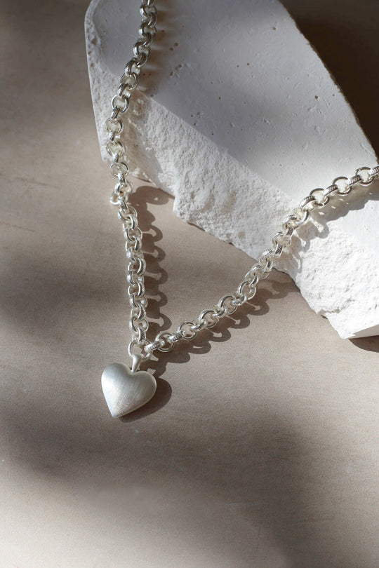 Tutti & Co Solace Silver Necklace featuring a delicate chain and elegant pendant, styled on a neutral background.