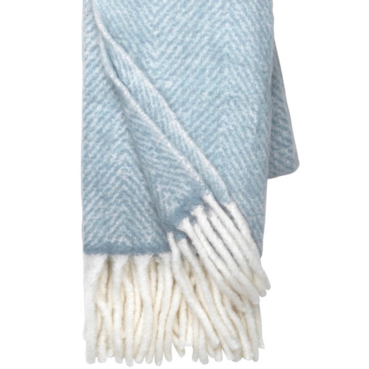 Dusty blue Mathea throw blanket from Cornucopia Home and Gift, showcasing soft, cozy fabric perfect for living room decor.