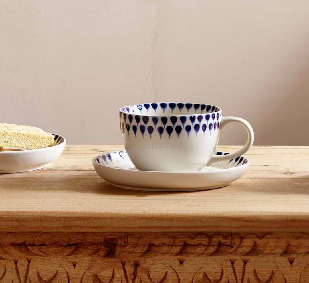 Indigo ceramic drop cup and saucer by Nkuku, featuring a smooth glazed finish, ideal for stylish coffee or tea serving.