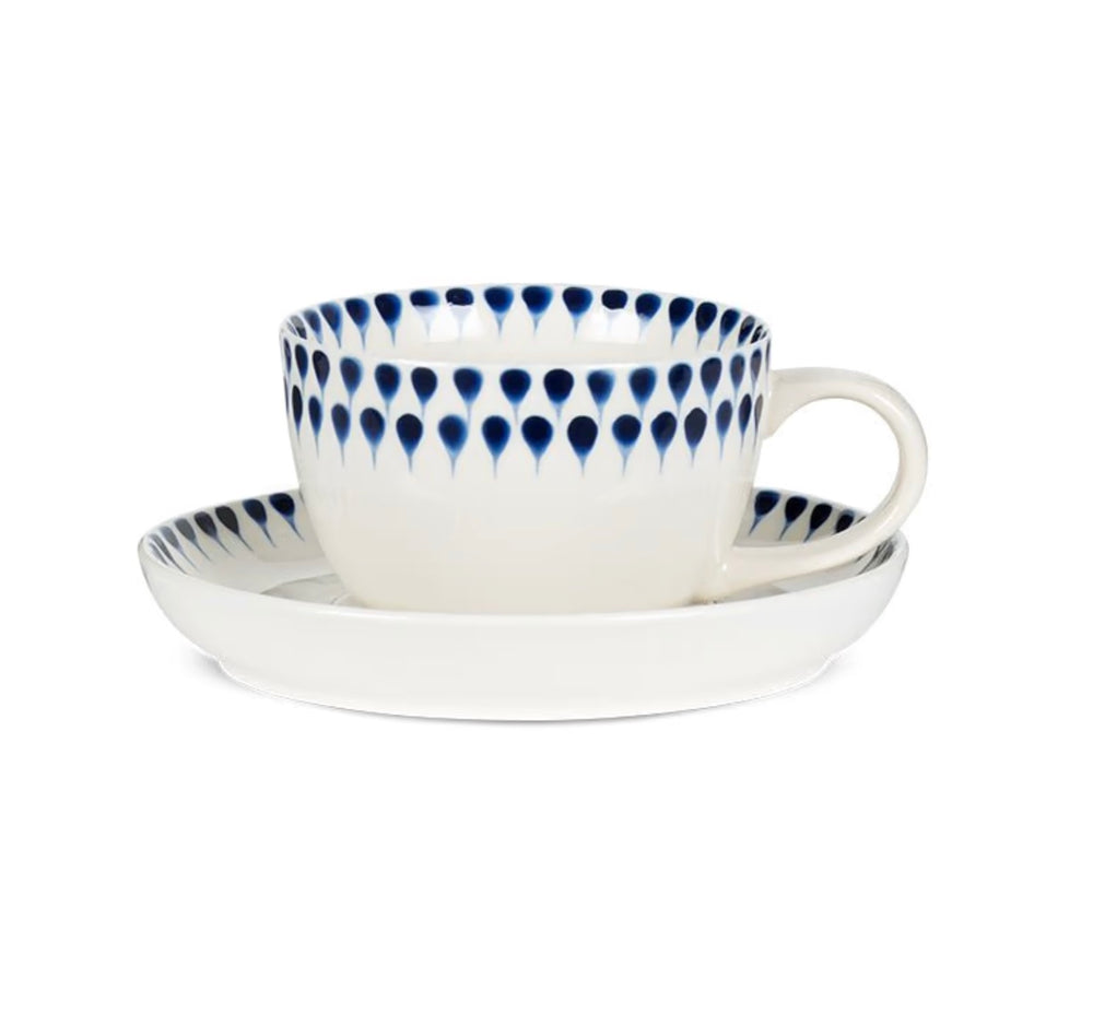 Indigo ceramic drop cup with matching saucer by Nkuku, featuring a glazed finish and elegant design, perfect for serving beverages.