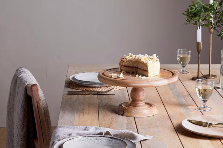 Nkuku recycled glass dome cake stand with a clear, rounded glass cover and a sturdy base, perfect for displaying baked goods.