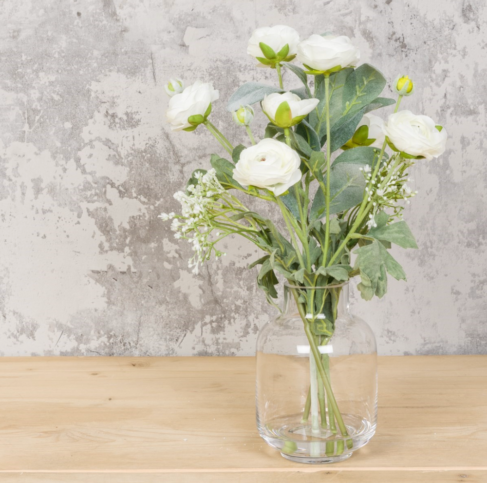 White ranunculus flowers in a glass bottle vase, arranged as a floral silk decor by Cornucopia Home and Gift.