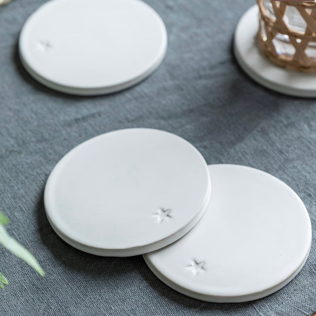 Set of four round white ceramic coasters from Garden Trading by Cornucopia Home and Gift, with a smooth, glossy finish.