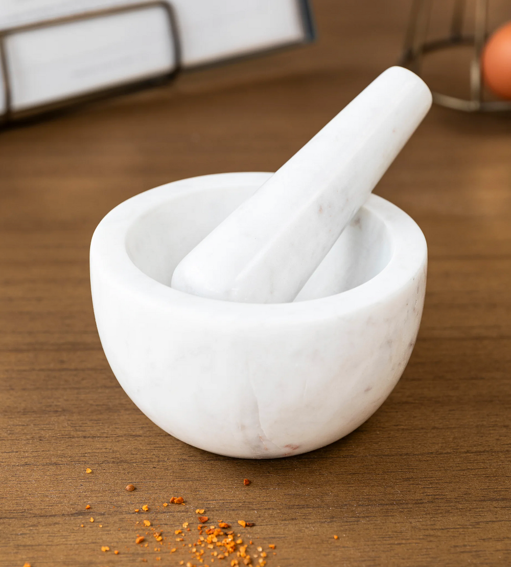 White Brompton Pestle and Mortar from Garden Trading by Cornucopia Home and Gift, shown on a countertop.
