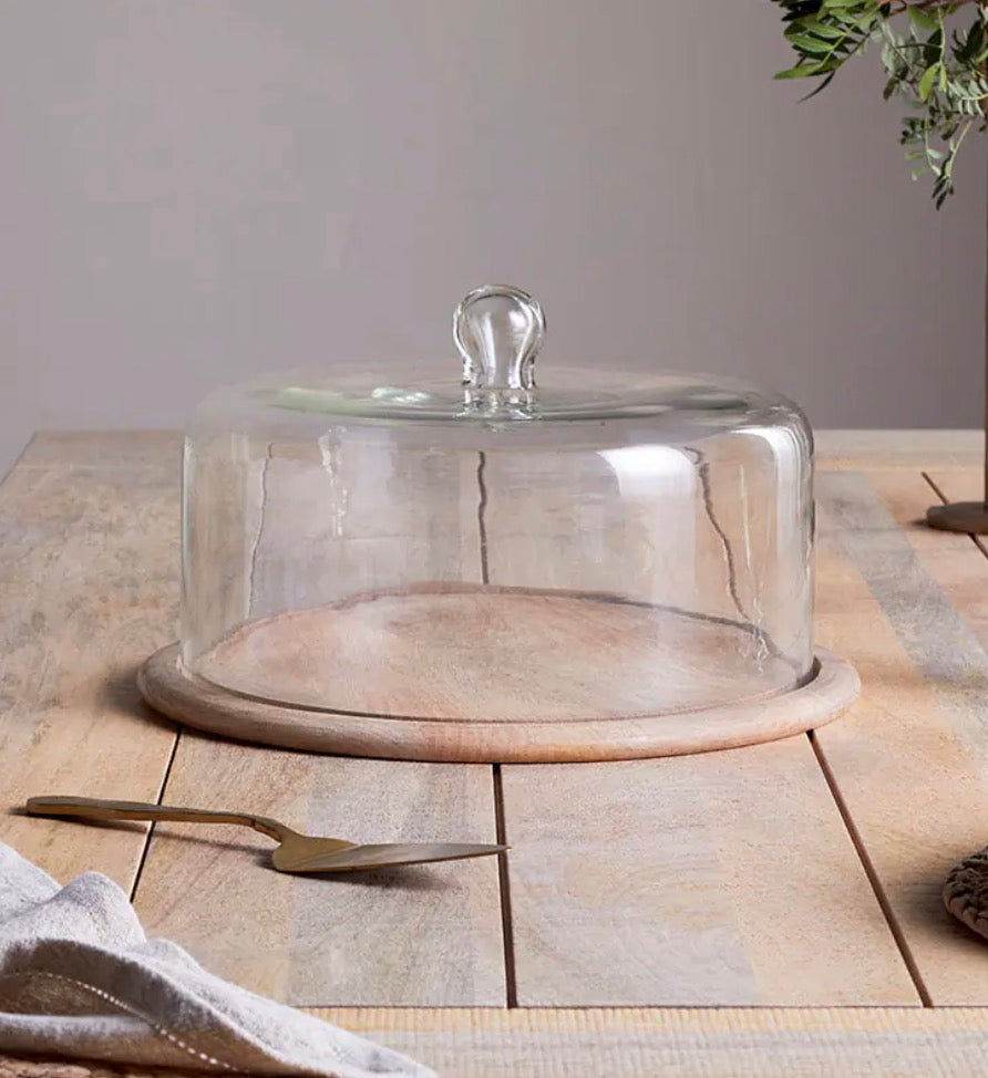 Recycled glass cake dome by Nkuku, showcasing a clear, eco-friendly cover with a rounded shape and sturdy base.