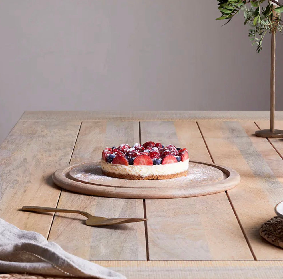 Recycled glass cake dome by Nkuku, clear round cover with a wooden base for displaying baked goods and desserts.