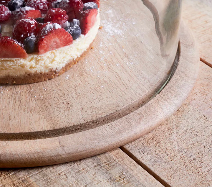 Recycled glass cake dome by Nkuku, showcasing a clear, elegant cover for desserts, with a rounded shape and sturdy base.