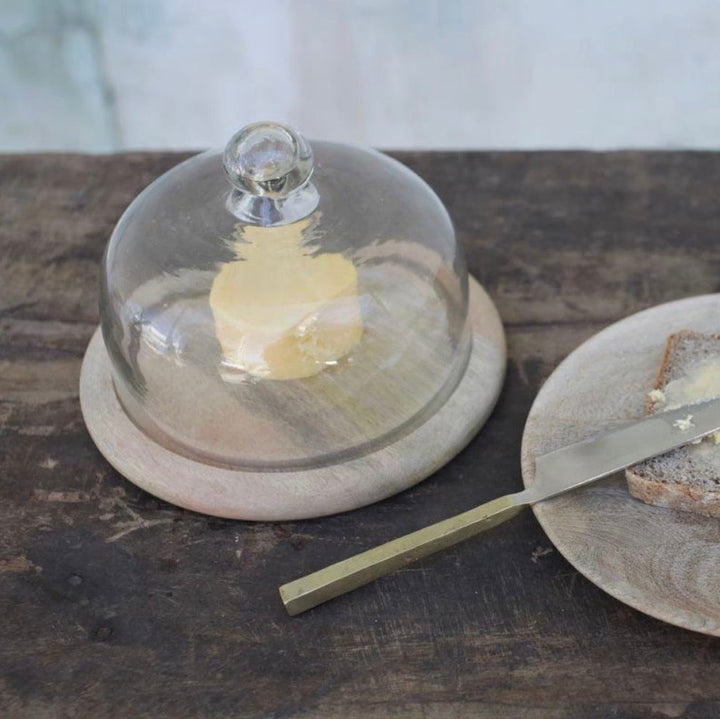 Clear recycled glass cake dome by Nkuku, featuring a sleek, transparent design perfect for showcasing baked goods.