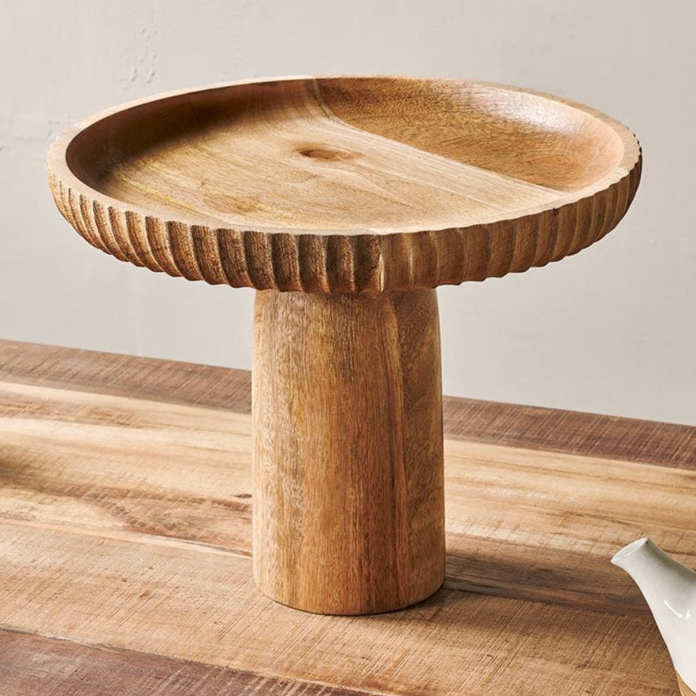 Wooden pedestal dish on a wooden surface with a neutral background