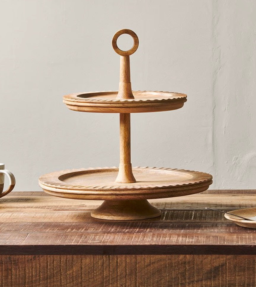 Nkuku Gavivi mango wood cake stand with a smooth, round surface and sturdy base for showcasing baked goods.