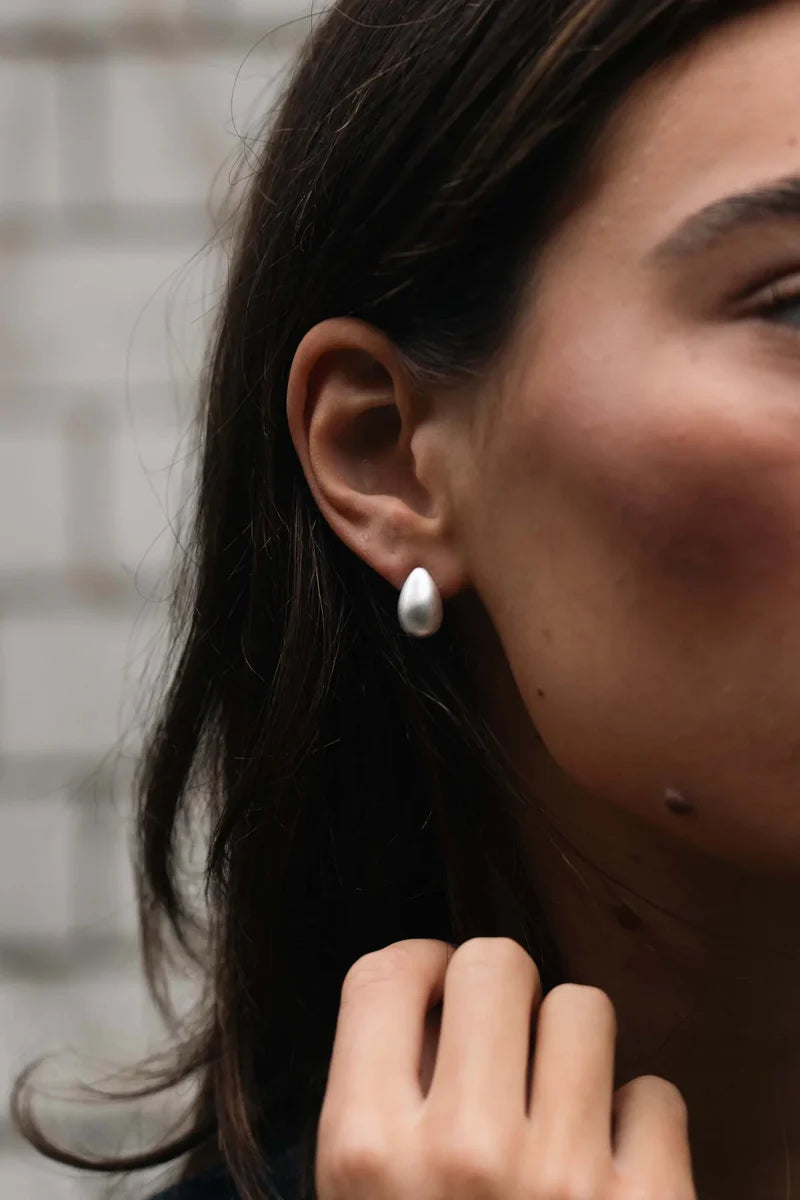 Silver teardrop earrings by Tutti & Co featuring sleek, elegant design, displayed on a neutral background.