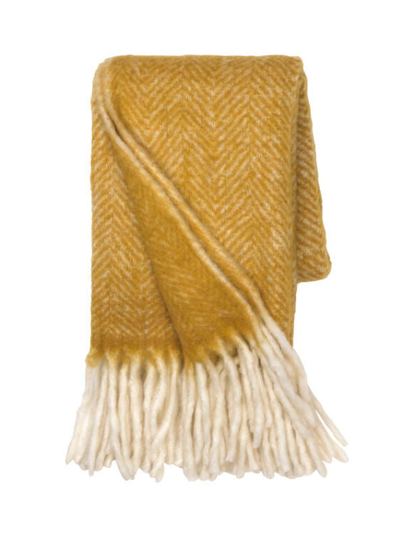 Mustard-colored wool throw blanket from Cornucopia Home and Gift's Cozy Living Mustard Mathea collection, draped on a sofa.