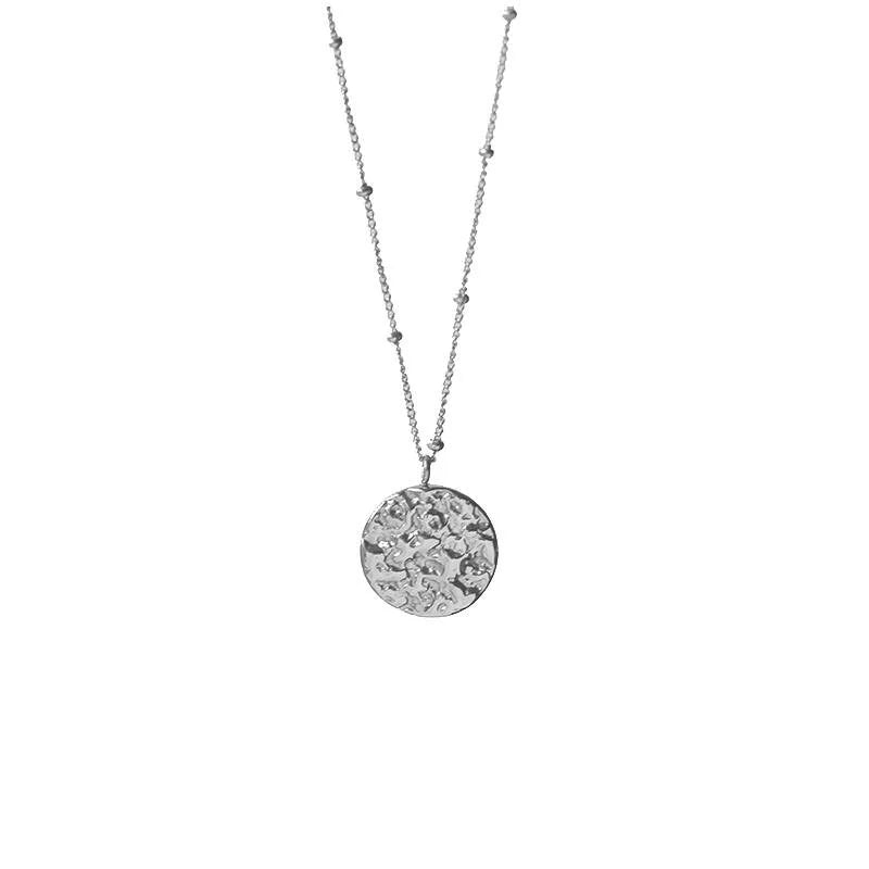 White leaf textured silver disc necklace from Cornucopia Home and Gift featuring a delicate, handcrafted jewelry design.