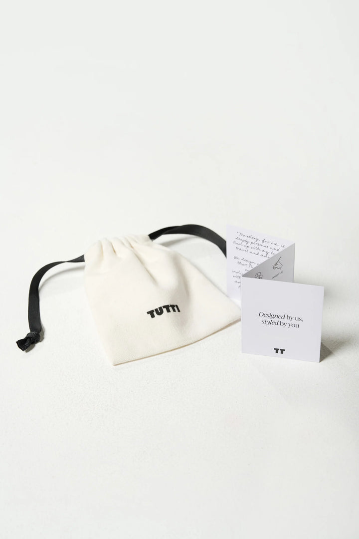 Silver Cosma Earrings by Tutti &amp; Co in a small pouch, showcasing their sleek, minimalist design and shiny finish.