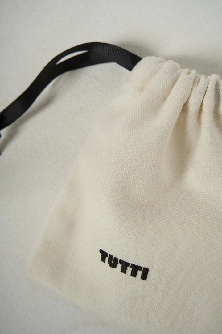 Silver Cosma Necklace by Tutti &amp; Co displayed in a pouch, showcasing its delicate chain and minimalist pendant design.