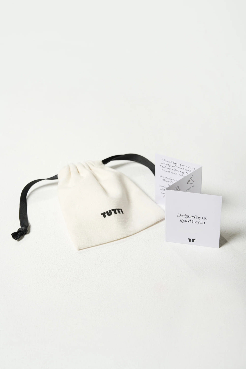 Gold Cosma Earrings from Tutti & Co, shown inside a soft pouch with the earrings visible and showcasing their elegant design.