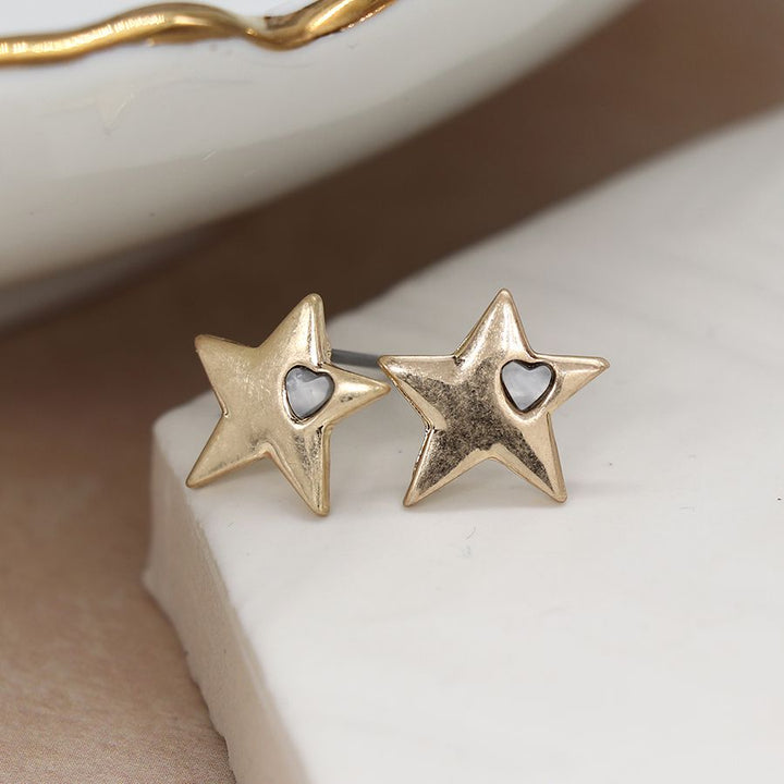 Worn gold star earrings from POM Jewellery by Cornucopia Worcester, featuring shiny gold star designs on small hoops.