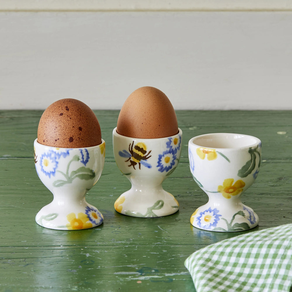 Emma Bridgewater Buttercup & Daisies set of 3 egg cups with floral pattern, displayed on a gray lifestyle background.