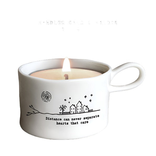 East of India porcelain tea light holder with "Distance Can Never Separate" inscription, featuring a handle and delicate design.