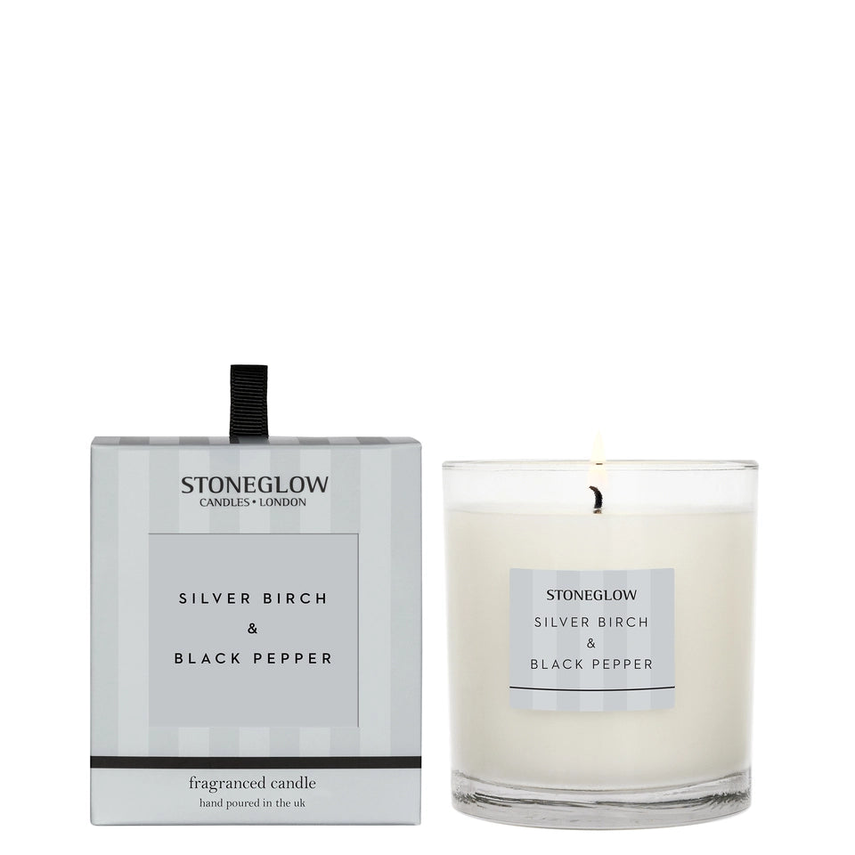 Stoneglow Modern Classics Silver Birch and Black Pepper candle in a sleek glass container with a lit wick.