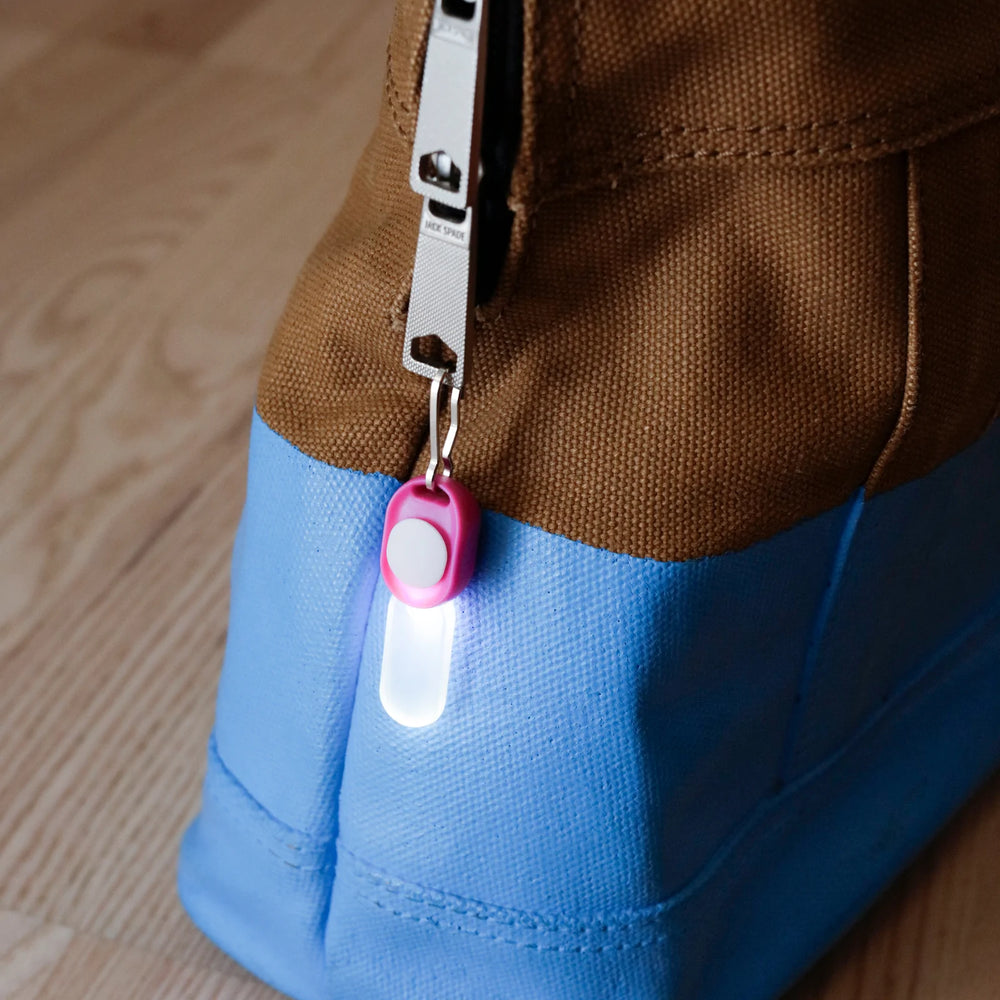 Kikkerland Zipper LED Light attached to a zipper, showcasing its compact design and bright illumination on a white background.