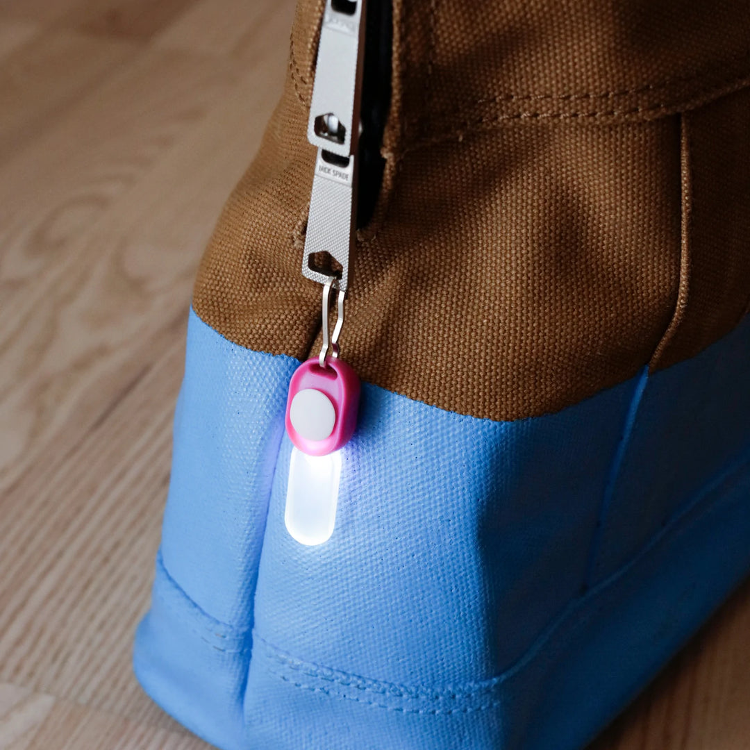 Kikkerland Zipper LED Light attached to a zipper, showcasing its compact design and bright illumination on a white background.