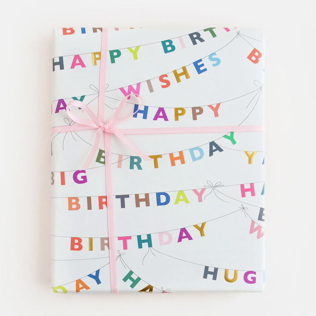 Caroline Gardner birthday bunting wrapping paper featuring colorful festive banners on a white background.