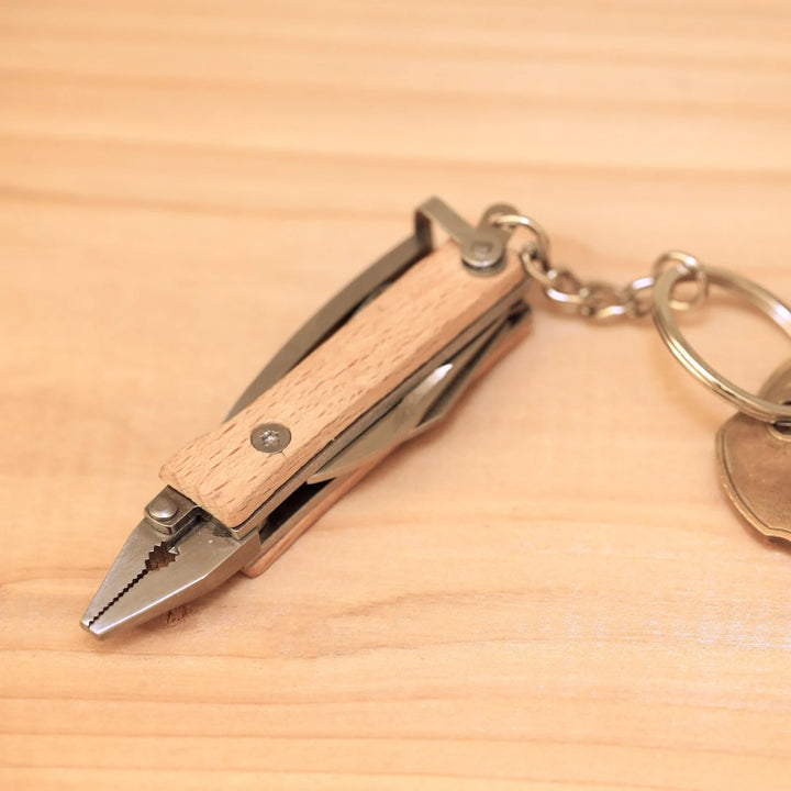 Kikkerland Mini Wood Pliers keychain tool with small wooden handles and metal gripping jaws, ideal for keychain or small tasks.