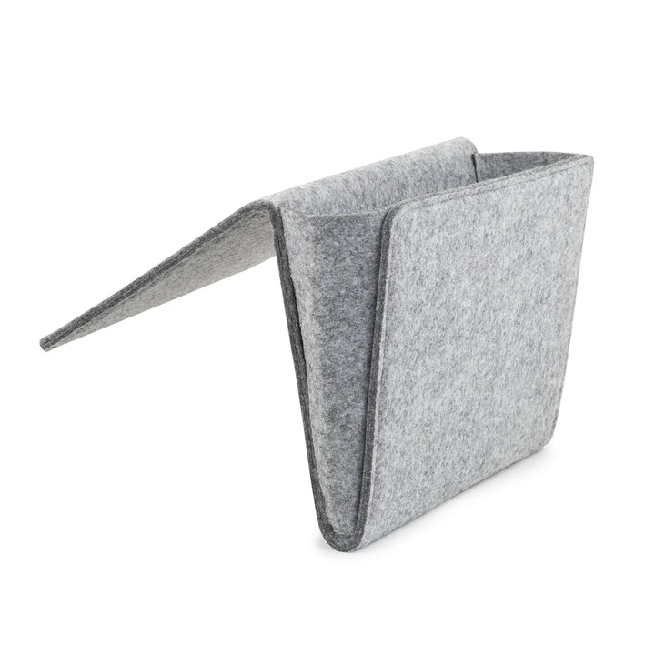 Kikkerland bedside pocket organizer hanging on a bedpost, featuring multiple compartments for easy bedside storage.
