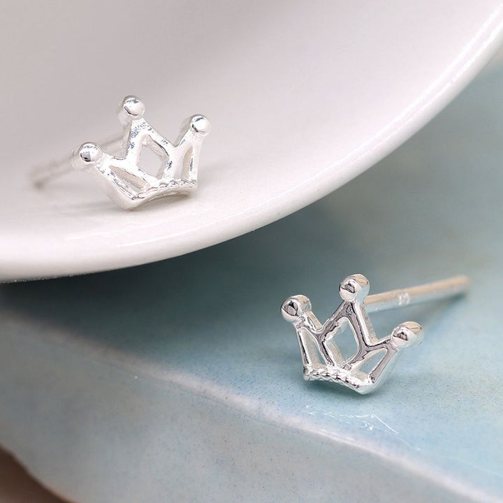 Tiny silver crown stud earrings by POM Jewellery from Cornucopia Worcester, featuring small, detailed crown designs on sterling silver studs.